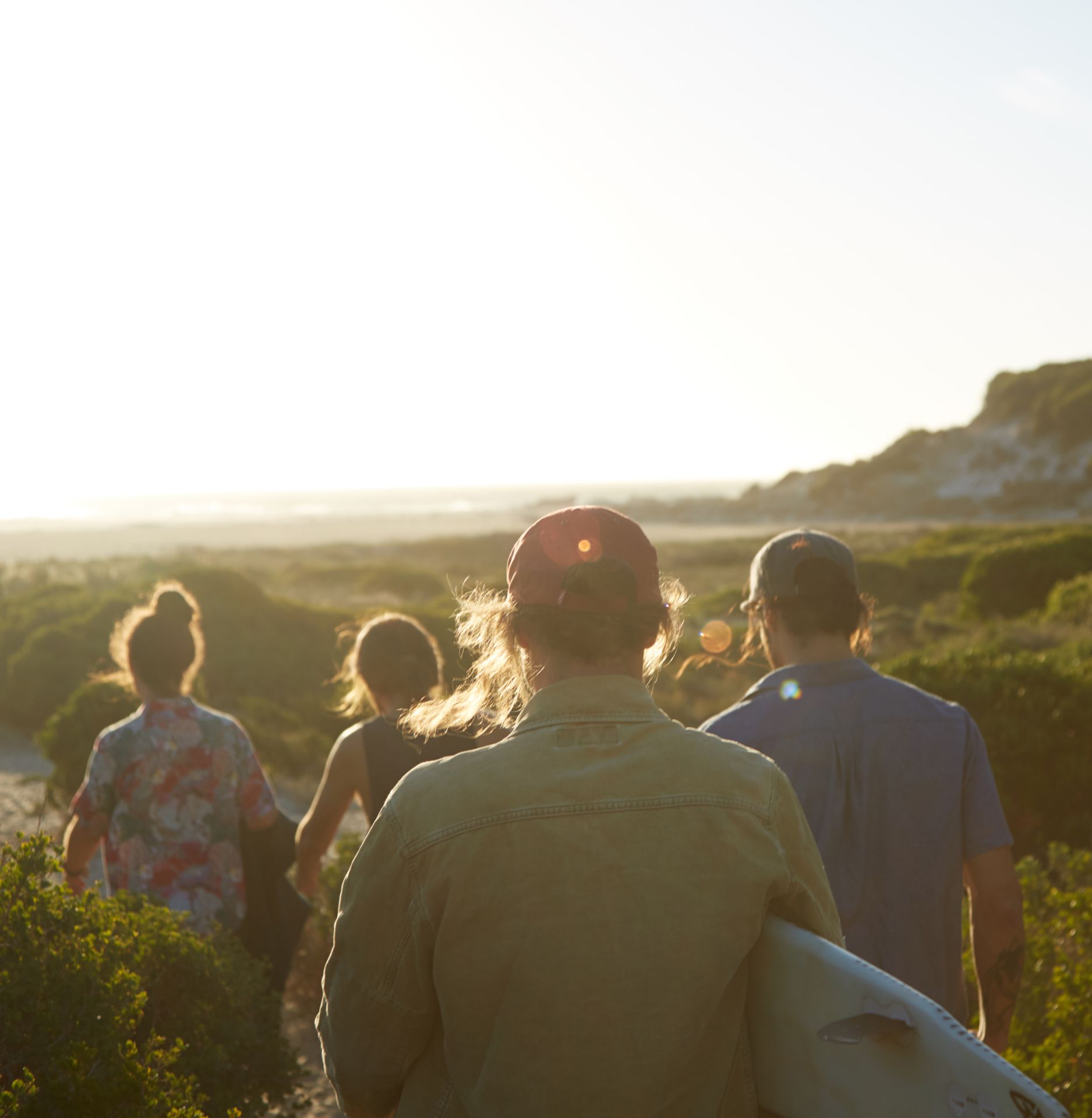 Friends on the path to the water, surfboard under an arm